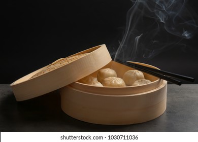 Bamboo steamer with tasty baozi dumplings on table