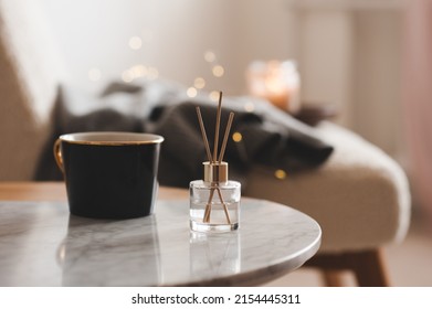 Bamboo sticks in bottle with scented candles and cup of tea on marble table closeup. Home aroma. Aromatherapy. Apartment living.  - Shutterstock ID 2154445311