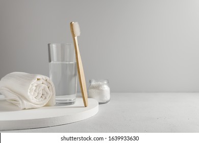 Bamboo toothbrush, glass of water, white a cotton towel and powder for brushing your teeth in jar. light gray concrete surface, gray backdrop. Biodegradable personal care products. No plastic concept. - Powered by Shutterstock