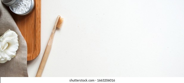 bamboo toothbrush with natural paste and beige cotton towel, flower on white background banner. Concept eco friendly, copyspase, zero waste.