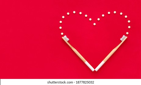 Bamboo toothbrushes and eco toothpaste in tablets. Creative heart on the red background. Valentines day concept. Plastic free, zero waste.