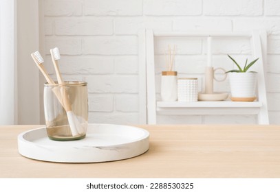 Bamboo toothbrushes in glass on wooden table with copy space