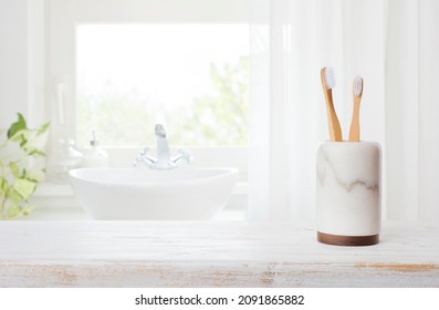 Bamboo toothbrushes in marble glass on blurred bathroom window background - Powered by Shutterstock