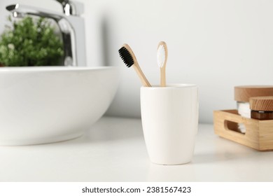 Bamboo toothbrushes on white countertop in bathroom - Powered by Shutterstock