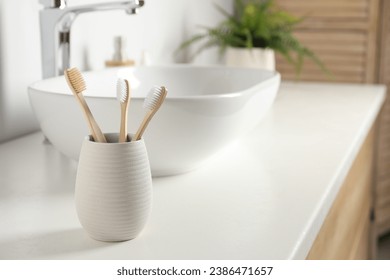 Bamboo toothbrushes on white countertop in bathroom, space for text - Powered by Shutterstock