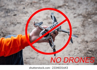 Ban drones. Quadcopter aerial photography is prohibited. No-fly zone for drones. A man holds a drone in his hand. New technologies in photo and video filming. Prohibition sign.