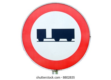 a ban on driving road sign for trucks with a trailer in the backround a wood