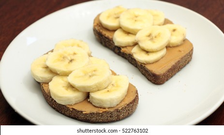 Banana And Almond Butter Toasts On White Plate