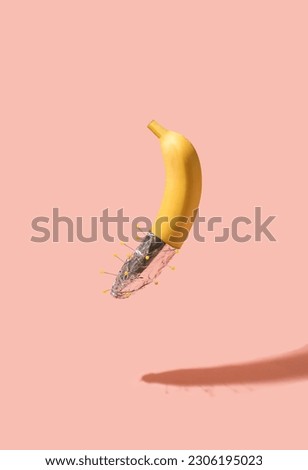Banana with aluminum foil with pins on bright pink background. Minimal food concept.