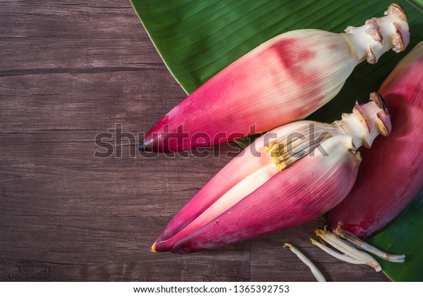 Banana\
blossom with banana leaves placed on an old wooden plates.top\
view.Banana blossom helps to nourish the\
blood.