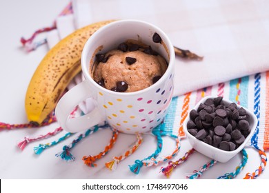 Banana Cake In Mug On Colors Rag With Chocolate Chips On White Marble