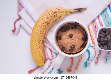 Banana Cake In Mug On Colors Rag With Chocolate Chips On White Marble