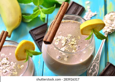 Banana and chocolate smoothie in a glass on a blue wooden table.