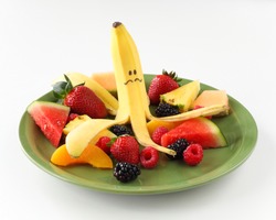 Banana With Funny Face On Plate Of Fruit Including Berries And Melons