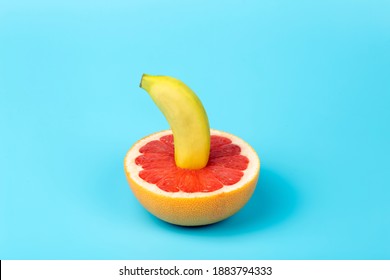Banana and grapefruit flat lay minimal composition on a blue background. A metaphor of sex, sexuality, vagina and penis.