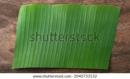 banana leaf on a wooden surface or table top, can be used as a plate, background texture, taken from above with copy space, backdrop for food photography