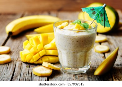 banana mango smoothie on a dark wood background. toning. selective Focus