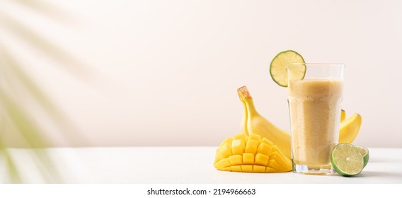 Banana Mango Smoothie In A Tall Glass On A Light Background. Diet Breakfast. Tropical Fruit Drink Concept