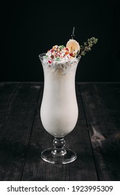 banana milkshake in a glass of harikane shape on a dark wood background