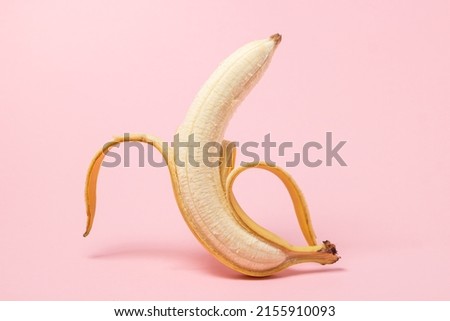 Banana on a pink background. Half peeled banana. tropical fruit
