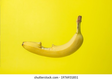Banana on a yellow background. Bright fruit. Bitten banana with peel