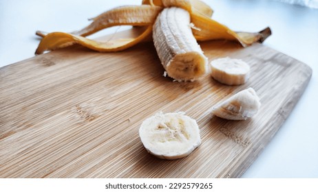 Banana with open panel and sliced round pieces on wooden board and white background. Ripe banana with peel cooking, Close up. Delicious sweet fruit dessert - Shutterstock ID 2292579265