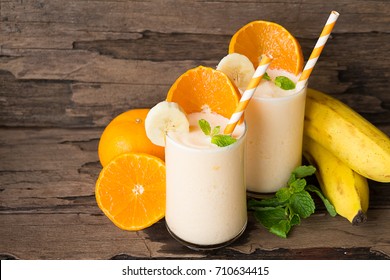 Banana And Orange Smoothies On A Beautiful Old Wooden Background.