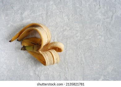 A Banana Peel Lies On A Gray Concrete Table. Zero Waste Concept. Banana Peel For Compost Or Home Fertilizer.