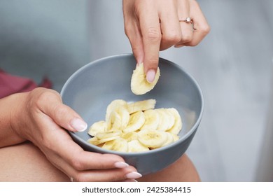 Banana salad background. Bananas slices in bowl. Woman hand holding fruit slices. Eating fruits with fingers. Banana pieces for breakfast. - Powered by Shutterstock