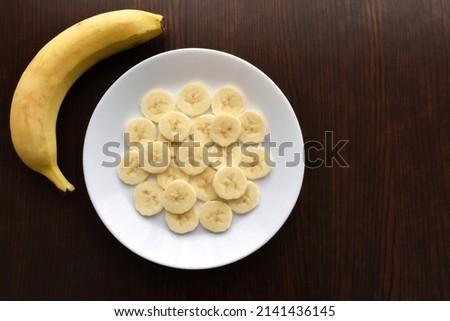 Banana slices on a white plate.  Copy space is on the right side.  Flat lay top view photo.  Food from above concept.