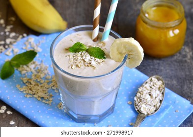 Banana Smoothie With Honey And Oats On A Wooden Table.