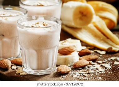 Banana smoothie with milk, oatmeal and almonds on the old wooden background, selective focus