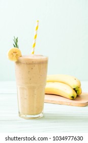 banana smoothies glass on wood table - Shutterstock ID 1034977630