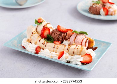 Banana split ice cream with syrup and strawberry on blue plate, top view. Chocolate, strawberry and vanilla ice cream scoops on plate, summer dessert - Powered by Shutterstock