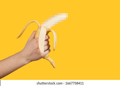 Banana as a symbol of male penis in hand on a yellow background hidden by censorship. Sexual masturbation and orgasm, impotence problem. Self-pleasure concept.