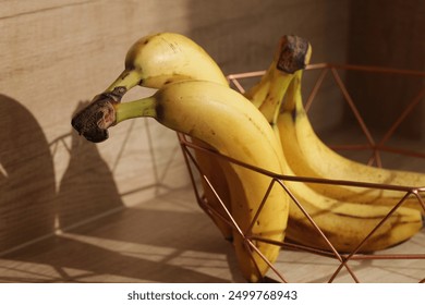 Bananas on wooden kitchen counter. Ripe bananas isolated on table. Sunlight fruits. Quick healthy morning snack. Yellow fruits with brown stains. Bananas in decorative metal bowl. Sun morning shadow - Powered by Shutterstock