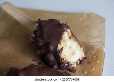 Bananas with peanuts on a stick. A piece is bitten off, the inner filling is visible. Close-up.