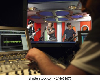 Band in recording studio with technician in foreground - Powered by Shutterstock