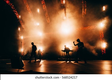 Band Silhouette. Сoncert Of Popular Group.  Rock Band Performs On Stage. Guitarist, Bass Guitar, Keyboard Player And Drums. Bright Light Show At The Stadium. 