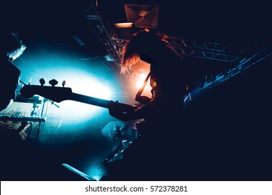 Band Silhouette. View of stage during rock concert with musical instruments and scene stage lights, rock show performance. Guitarist plays solo on stage. Electric guitar. - Shutterstock ID 572378281