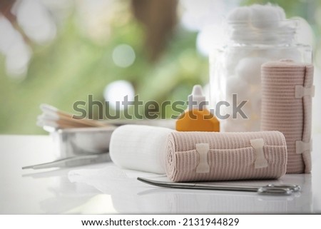 Bandage and first aid kit on white table, bokeh background.