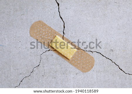 A bandage is stuck to a crack in the concrete wall.