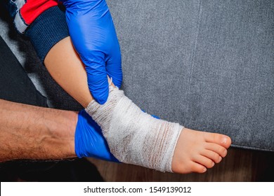 Bandaging Of The Child's Foot. Health And Pharmaceutical Concept, Child Health Problems. The Doctor Bandages And Stiffens The Child's Foot, Ankle. Sprain Or Fracture Of The Leg.