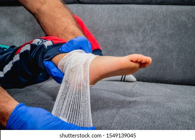 Bandaging Of The Child's Foot. Health And Pharmaceutical Concept, Child Health Problems. The Doctor Bandages And Stiffens The Child's Foot, Ankle. Sprain Or Fracture Of The Leg.