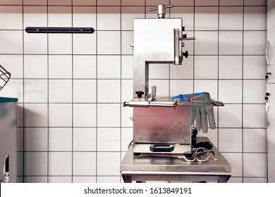 Bandsaw machine for cutting meat and a chainmail glove for protection in a slaughterhouse. Butchery equipment. 