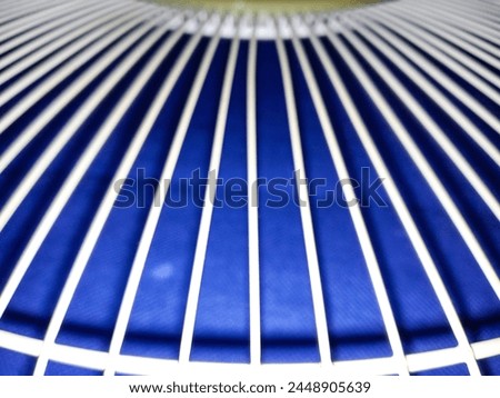 Bandung, Apr 11, 2024 : Disfocus of white curve line pattern wire which is blower fan cover that placed on blue fabric after clean at home.