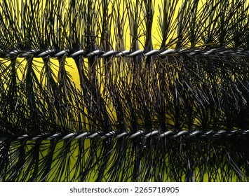 Bandung, Feb 22, 2023 : Abstract line pattern of black plastic Viber that attahaced by silver aluminium wire which is cleaner on yellow cardboard as background.