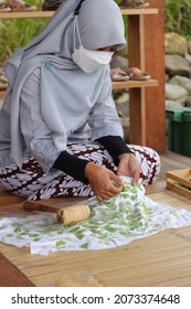 Bandung, Indonesia, April 09 2021: A Muslim woman wearing a kebaya and a mask is making ecoprints or making motifs from leaves on cloth.