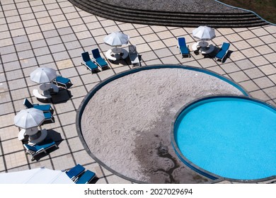 Bandung, Indonesia - Aug 2011: Close Up Top View Of Swimming Pool With Turquoise Color Water And Sunbathing Couch And Umbrellas. No People. 