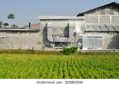 Bandung, Indonesia - August, 7 2021: Juxtaposition of rice fields and factories. The distinction between traditional culture and industrial technological advances